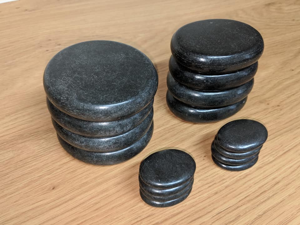 Smooth black basalt hot stones stacked on wooden surface for spa and massage therapy